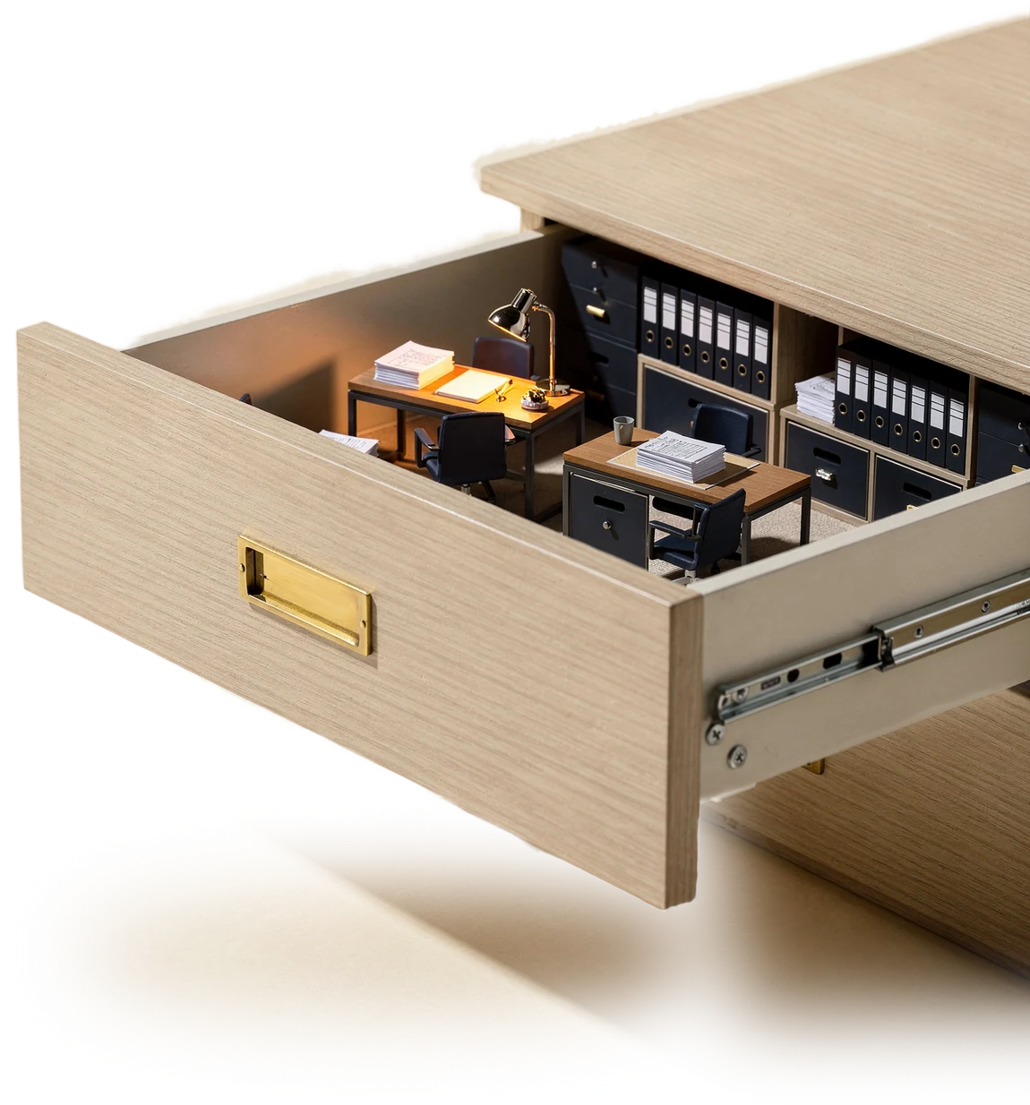 An open filing cabinet drawer containing a complete miniature back office with lit desks, binders and document stacks